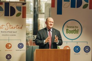 Senator Coons speaking at a wooden podium