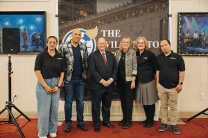 Group of people standing around Senator Coons smiling